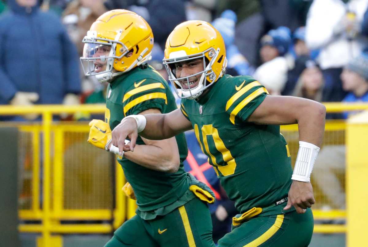 Jordan Love smiles as he runs off the field with wide receiver Christian Watson next to him